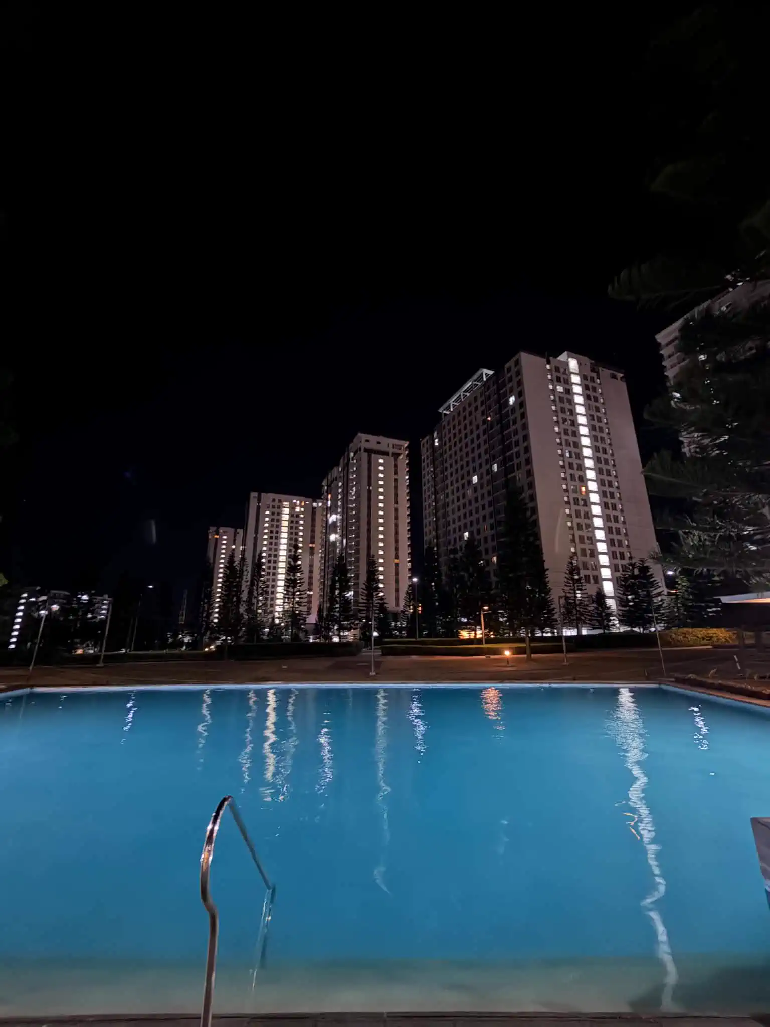 Lit swimming pool with Wind Residences towers at night